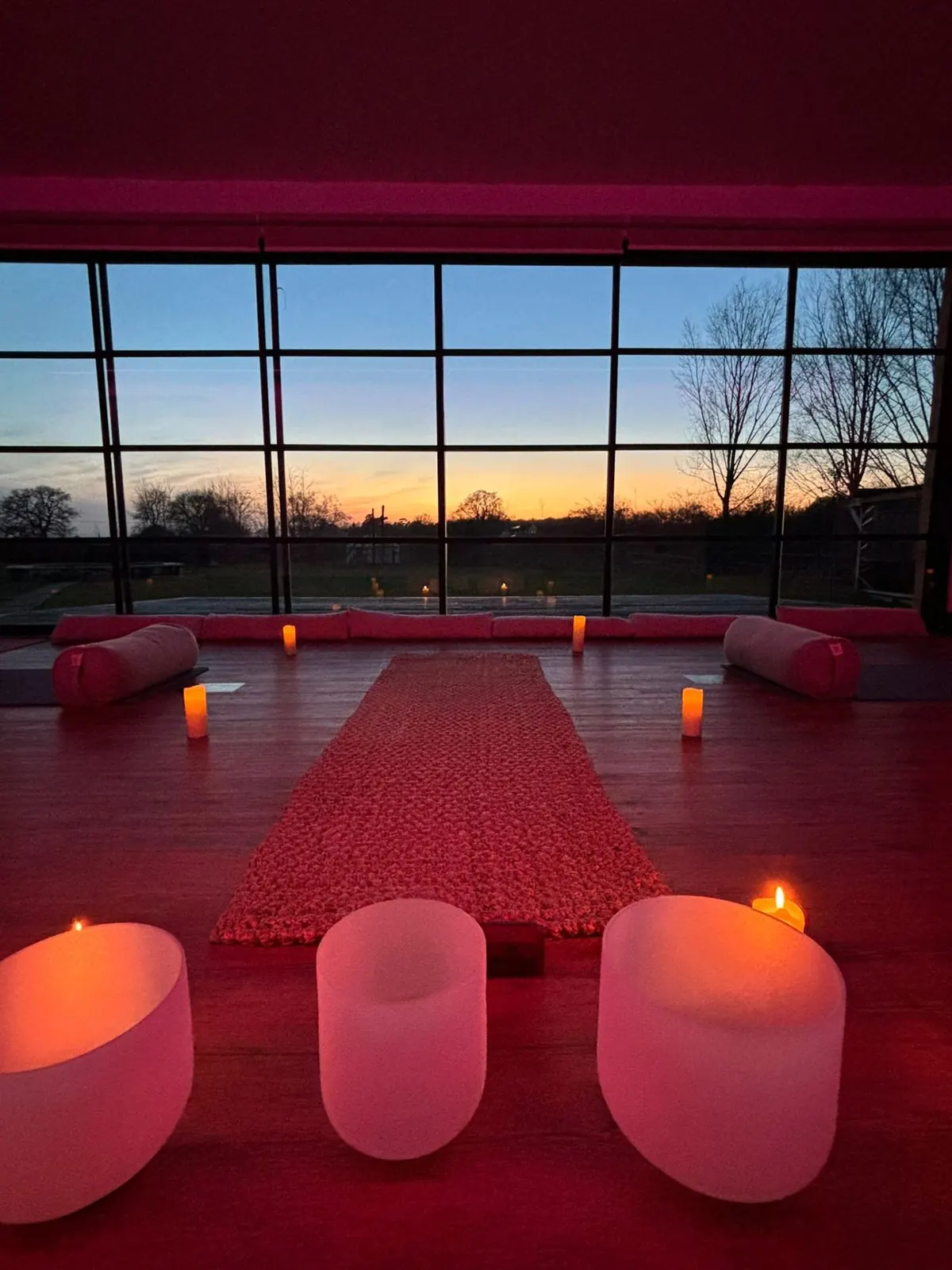 Candlelit yoga space at sunset with crystal bowls